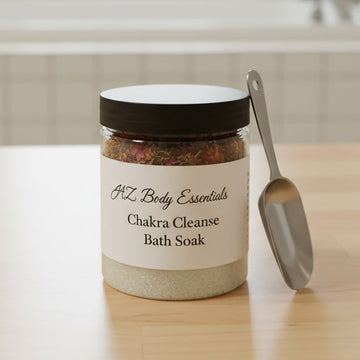 Jar of 'Chakra Cleanse Bath Soak' with a scoop on a wooden surface, bathroom in the background